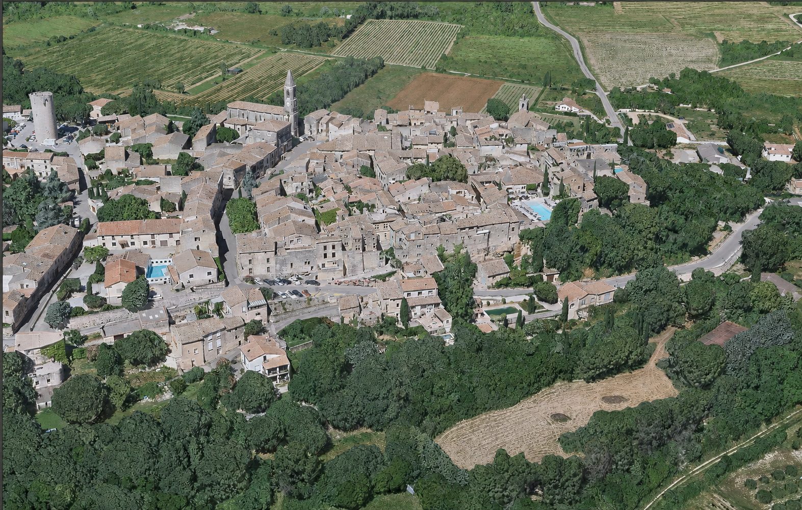 Vue aérienne de Castillon-du-Gard : toits de tuiles, clocher et tour médiévale au milieu des vignes et de la garrigue